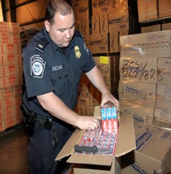 Counterfeiting is a world-wide problem... a US Customs and Border Protection officer opening a case of toothpaste, believed to be counterfeit. (Image: US Customs [transferred by Gobonobo/Originally uploaded by Wikiwatcher1], via Wikimedia Commons)