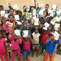 Members of the Thusanang reading club in Thusanang holding up their cut-out-and-keep storybook version of 'Where is Patch' by Wendy Hartmann.
