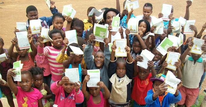 Members of the Thusanang reading club in Thusanang holding up their cut-out-and-keep storybook version of 'Where is Patch' by Wendy Hartmann.