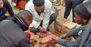 Ismail Rothman, Corobrik Building training coordinator shows CPUT learners how to lay paving.