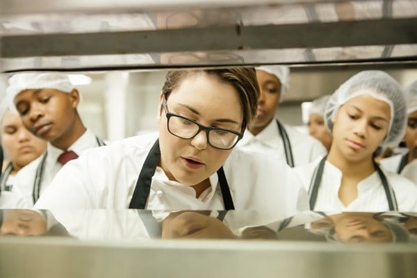 (Left) Abongile Mcutshenge from Sinethemba High School, and (Right) Bronwyn Louw from Ravensmead High School look on as GrandWest Chef Roxy Fabricius (centre) demonstrates her culinary skills.