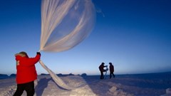 Researchers release a balloon carrying instruments to measure ozone levels above Antarctica. ,