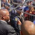 Mineral Resources Minister Gwede Mantashe talks to protesters through the locked gates of the Uitkyk Community Hall in Lutzville on Friday. Photo: John Yeld