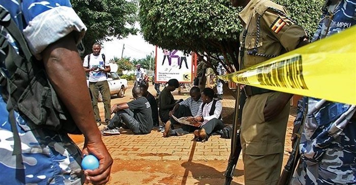 Ugandan journalists sit outside the office of the Daily Monitor, which was closed by armed police. The Monitor's website was recently ordered to suspend publication over a regulatory dispute. (Isaac Kasamani/AFP)