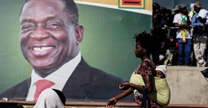 A woman walks in front of a picture of President Emmerson Mnangagwa in Bulawayo, in June 2018. Authorities in the Zimbabwean city detained documentary filmmaker Zenzele Ndebele on March 21. Credit: CPJ/AFP/Zinyange Auntony.