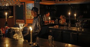 A barman using candle light as another rolling blackout affects large parts of South Africa’s biggest city, Johannesburg. Epa/Kim Ludbrook