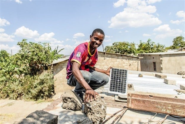 Steven Miyoba shows off the ReadyPay solar panel on the roof of his house, on the outskirts of Lusaka. “Before it would be dark at 6pm and we didn’t have any lighting. Now, we have a trusted brand that even my daughter knows how to use.” Image credit: Jason Mulikita, REEEP