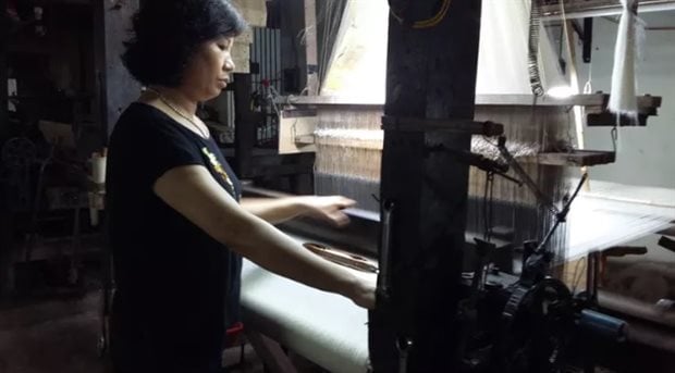 An artisan is working with a silk weaving loom in her workshop. Author provided