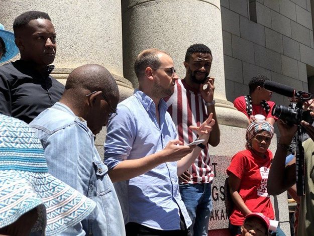 Michael Clarke, researcher for housing activist organisation Ndifuna Ukwazi, explains to supporters what has been happening inside court during Monday’s lunch break. Photo: Madison Yauger