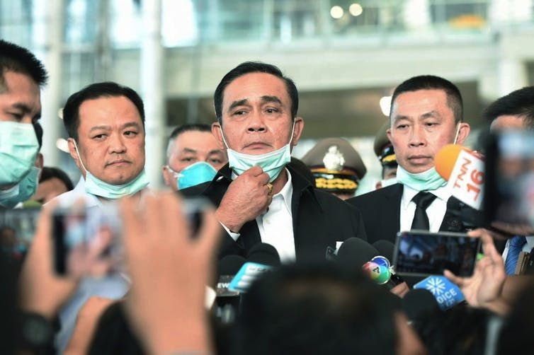 Thailand Prime Minister Prayuth Chan-ocha, centre, removes his face mask to speak to journalists during a visit to the Suvarnabhumi International airport to inspect measures in place to monitor passengers for the coronavirus. Thai Government Spokesman's office via AP