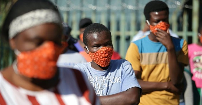 Community members wearing protective face masks as they queue for aid in Zandspruit informal settlement, north of Johannesburg. Phill Magakoe/AFP via Getty Images