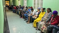Queue of seated outpatients, waiting patiently inside a provincial hospital corridor in Port Elizabeth. Shutterstock