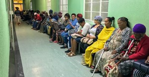 Queue of seated outpatients, waiting patiently inside a provincial hospital corridor in Port Elizabeth. Shutterstock