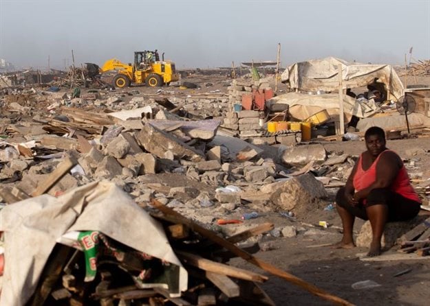 A woman sits at a site in James Town, Accra, demolished in May 2020 to make way for a new fishing port complex. Photo by Nipah Dennis/AFP via Getty Images