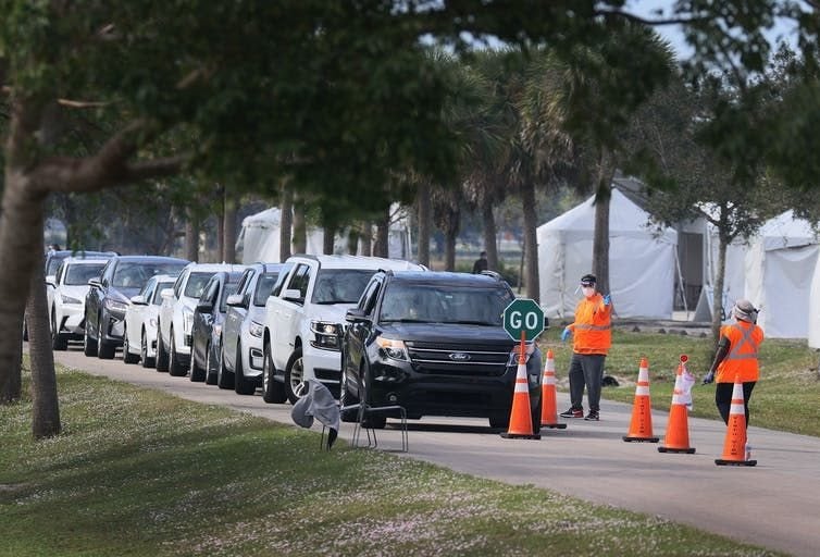 In Davie, Fla., Department of Health workers direct cars at a drive-thru vaccination site.