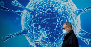 FILE PHOTO: A man wearing a protective face mask walks past an illustration of a virus outside a regional science centre amid the coronavirus disease (Covid-19) outbreak, in Oldham, Britain August 3, 2020. REUTERS/Phil Noble/File Photo