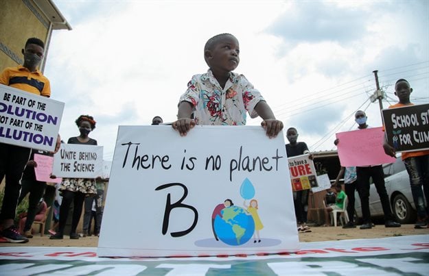 A child stands among Ugandan climate change activists holding placards advocating for climate change. Reuters/Abubaker Lubowa