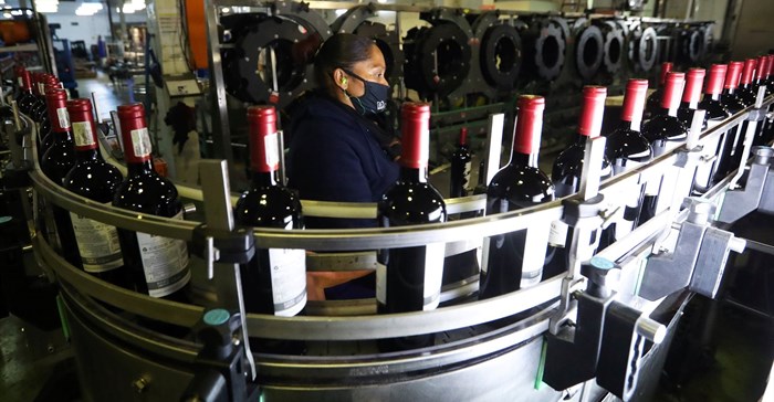 A worker checks bottles of wine coming out of a production line at Nederburg Wine Estate in Paarl, South Africa, 8 July 2020. Reuters/Mike Hutchings