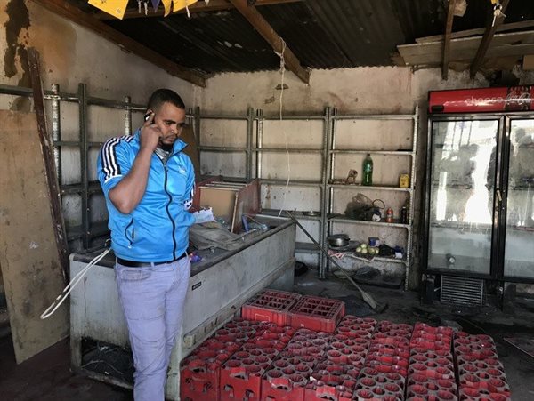 Ales Gedigano stands inside Sayabo Wodimu’s shop. He said he had been there since the morning to make sure that what remained after the looting was safe.