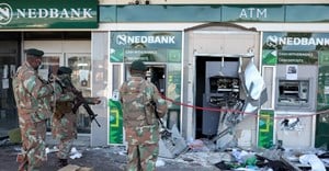 Members of the military look at damaged ATM machines outside a bank as the country deploys army to quell unrest linked to jailing of former President Jacob Zuma, in Soweto, South Africa, 13 July, 2021. Reuters/Siphiwe Sibeko