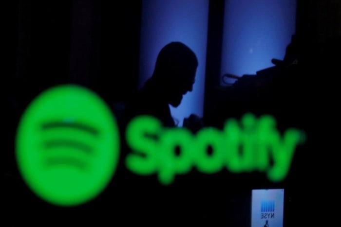 A trader is reflected in a computer screen displaying the Spotify brand before the company begins selling as a direct listing on the floor of the New York Stock Exchange in New York, US, on 3 April 2018. Reuters/Lucas Jackson/File Photo