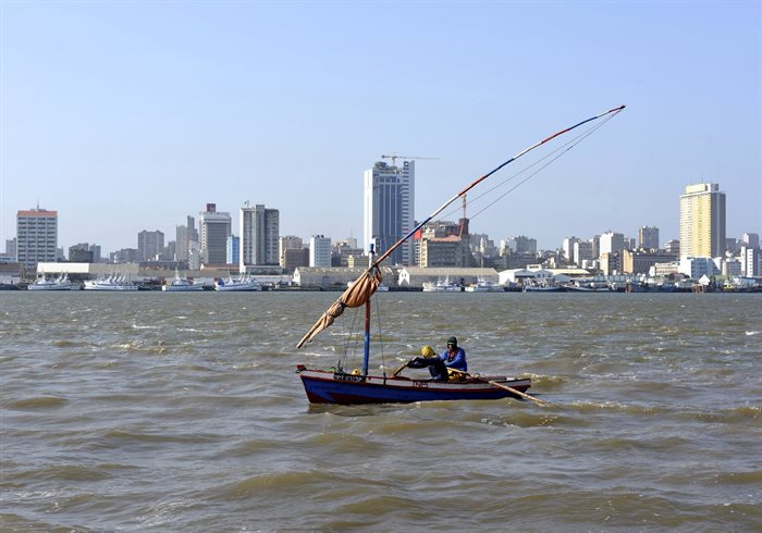Traditional fishing boats sail as Mozambique's tuna fleet sits in dock beneath Maputo's skyline. Reuters/Grant Lee Neuenburg