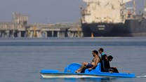 People enjoy the water while container ships park near the El Ain El Sokhna port before entering the Suez Canal, Egypt, 25 September 2020. Reuters/Amr Abdallah Dalsh