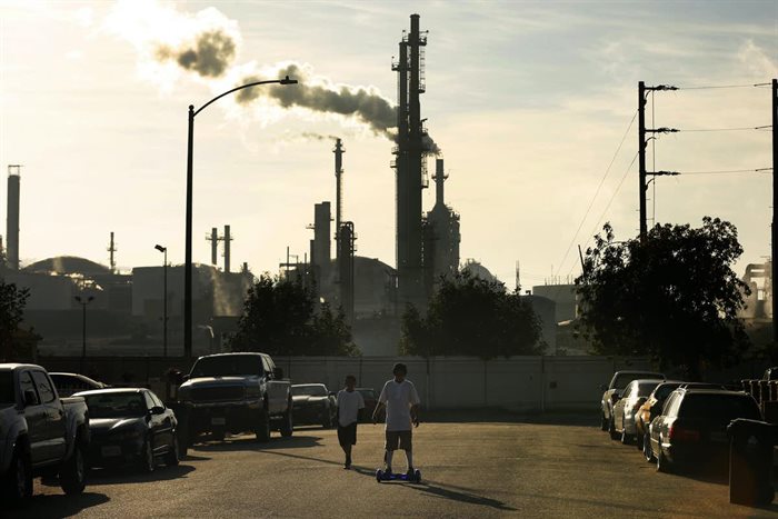 Kids play near homes in the shadow of an oil refinery. | Source: Rick Loomis/Los Angeles Times via Getty Images.
