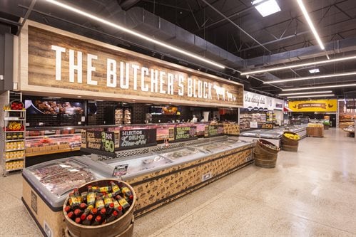 The state-of-the-art butchery at Food Lover's Market William Moffett boasts an LED screen that creates appetite appeal through value-adding recipe ideas, while effectively promoting products throughout the store through cross-merchandising. The butchery look and feel is a merge of old -school and artisanal, with a recessed wood look bulkhead and 2D farm animals and slick black tiles.