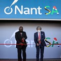 Source: REUTERS/Shelley Christians. Cyril Ramaphosa and Dr. Patrick Soon-Shiong cut a ribbon, while Premier of the Western Cape Alan Winde looks on.