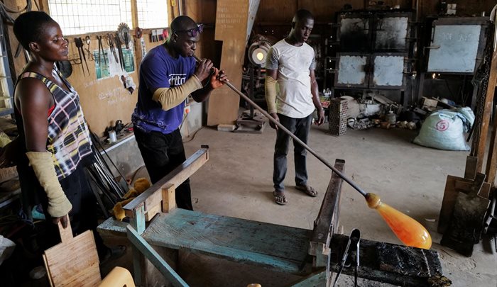 Ghanaian glassblower Michael Tetteh, 44, assisted by members of his staff, blows glass at his glassware manufacturing workshop in Krobo Odumase, Ghana on 15 March 2022. Source: Reuters/Francis Kokoroko