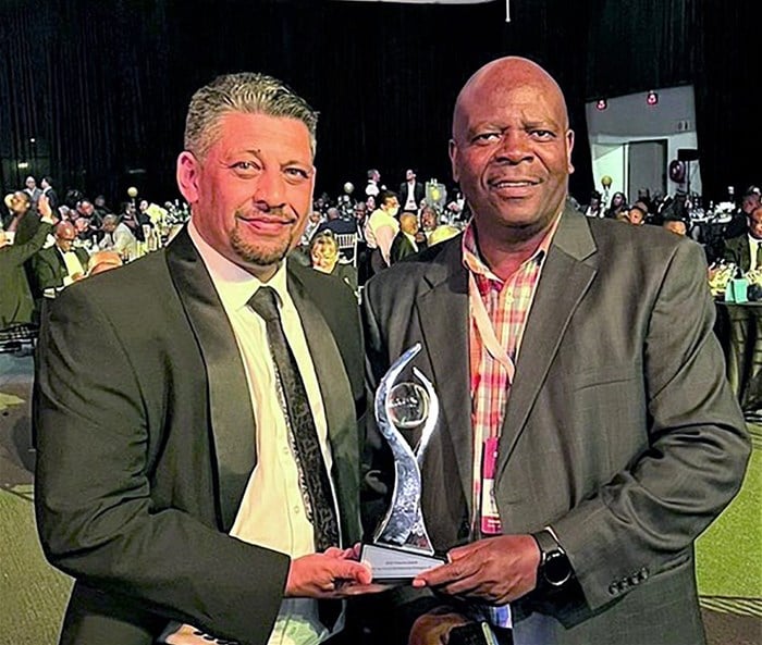 Lee Callakoppen, principal officer, and Oupa Komane, chairman of Bonitas Medical Fund, proudly holding the Titanium Award for Operational Performance.