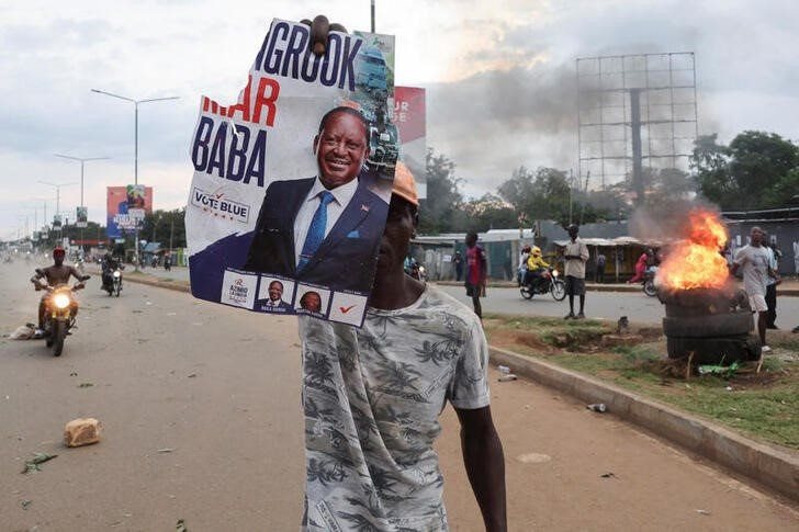A demonstrator holds up a poster of Kenya's opposition leader and presidential candidate Raila Odinga, as protests erupt after the presidential election results were announced, declaring Deputy President William Ruto the winner, in Kisumu, Kenya 15 August 2022. Reuters/Baz Ratner