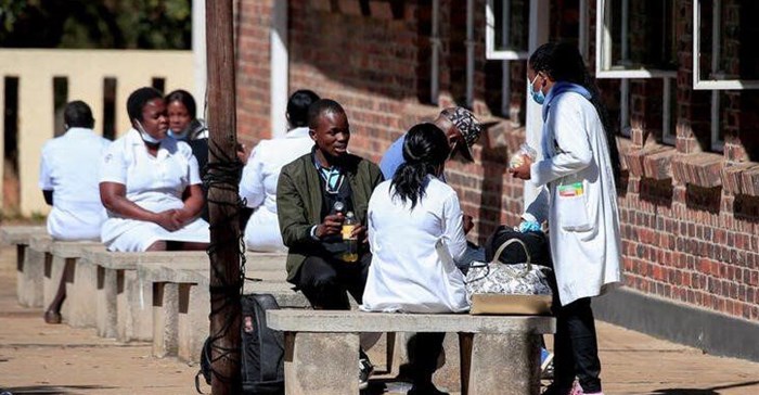 Source: Reuters. Zimbabwean medical workers sit outside Sally Mugabe Hospital during a strike by state doctors and nurses to press for higher pay, in Harare, Zimbabwe, June 20, 2022.