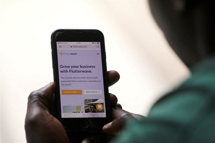 A man poses as he displays the Flutterwave homepage on a mobile phone screen in Abuja, Nigeria on 21 January 2020. Reuters/Afolabi Sotunde/File Photo