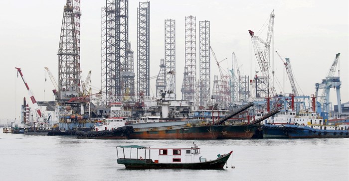 Offshore drilling platforms (rear) stand together at a dock yard near Singapore port. 2015. Source: Reuters/Tim Wimborne
