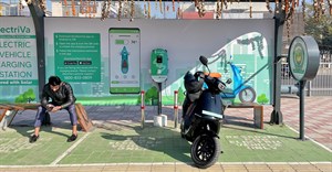 Source: Reuters. A man checks his mobile phone as he waits while recharging his Ola electric scooter at an electric vehicle charging station in New Delhi, India, 12 February, 2022.