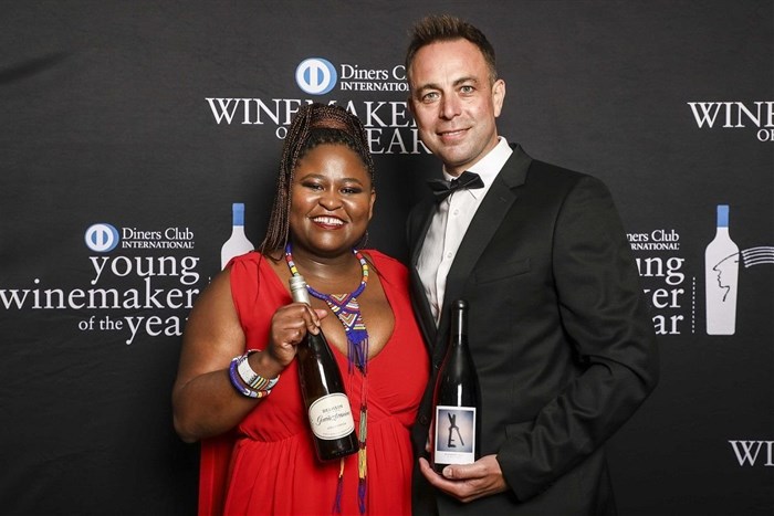 The winners of the 2023 Diners Club Young Winemaker and Winemaker of the Year awards holding their winning wines - Left: Nongcebo Langa (2023 Young Winemaker of the Year) with her 2022 Delheim Gewürztraminer, and Right: Tertius Boshoff (2023 Winemaker of the Year) with his 2020 Stellenrust ArtiSons Blueberry Hill Shiraz.