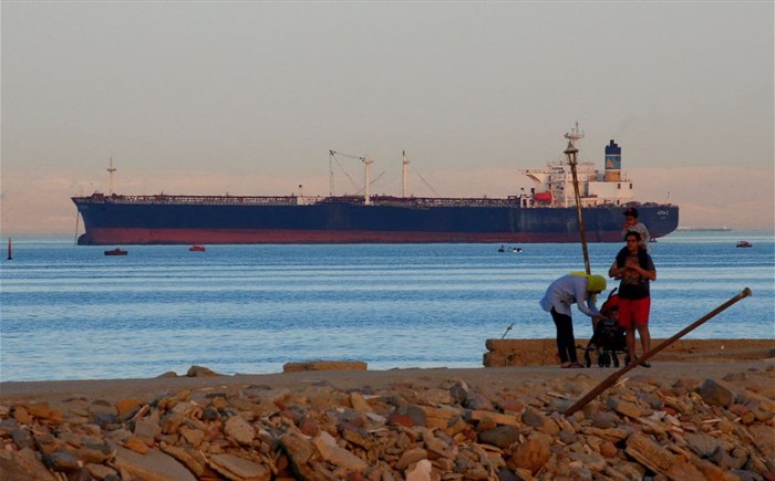 People walk on the beach as a container ship crosses the Gulf of Suez towards the Red Sea before entering the Suez Canal, in El Ain El Sokhna in Suez, east of Cairo, Egypt April 24, 2017. Picture taken April 24, 2017. REUTERS/Amr Abdallah Dalsh/File Photo