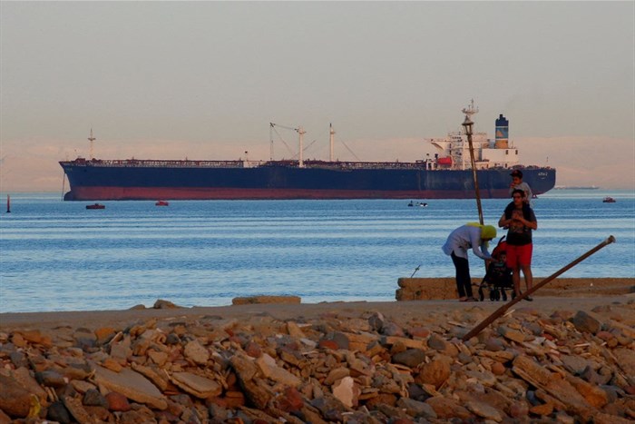 People walk on the beach as a container ship crosses the Gulf of Suez towards the Red Sea before entering the Suez Canal, in El Ain El Sokhna in Suez, east of Cairo, Egypt April 24, 2017. Picture taken April 24, 2017. REUTERS/Amr Abdallah Dalsh/File Photo