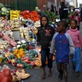 Children walk past a vegetable stall in Soweto 23 July 2015. Reuters/Siphiwe Sibeko/file photo