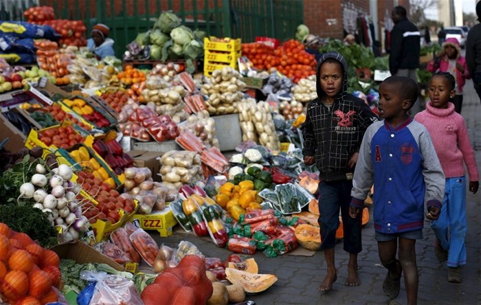 Children walk past a vegetable stall in Soweto 23 July 2015. Reuters/Siphiwe Sibeko/file photo