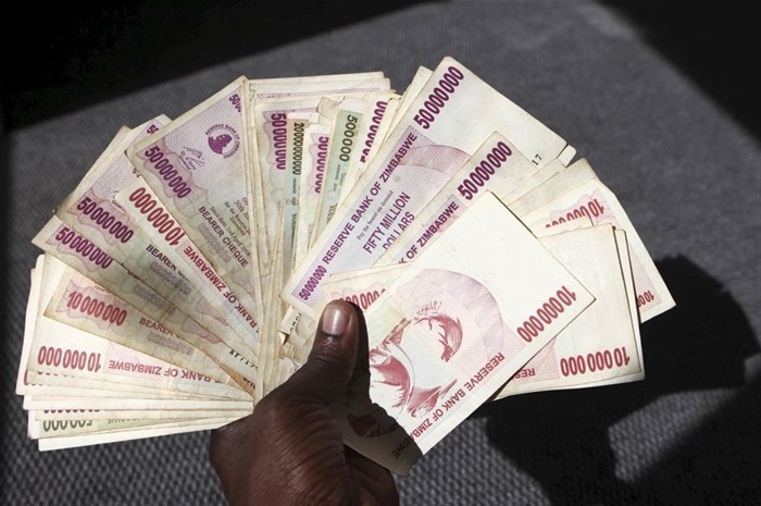 A man poses with a handful of Zimbabwean dollars at a bank in central Harare, 15 June 2015. Zimbabweans began exchanging old notes of local dollars for US dollars, as President Robert Mugabe's government seeks to officially bury the worthless currency. Reuters/Philimon Bulawayo/File Photo