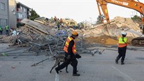 A rescue worker walks with a dog past the site where construction workers are trapped under a building that collapsed in George. Source: Reuters/Esa Alexander