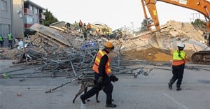 A rescue worker walks with a dog past the site where construction workers are trapped under a building that collapsed in George. Source: Reuters/Esa Alexander
