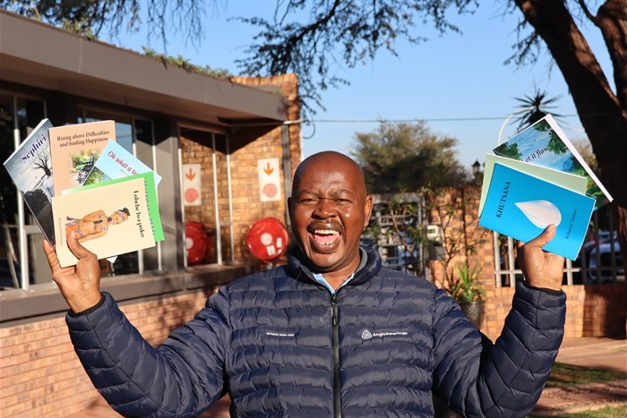 Kumba Iron Ore's Walter Khumo showcasing the newly published books. Image supplied.