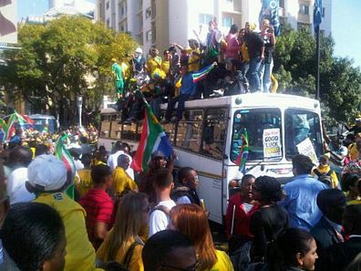 Bafana Bafana supporters climbing on a bus.